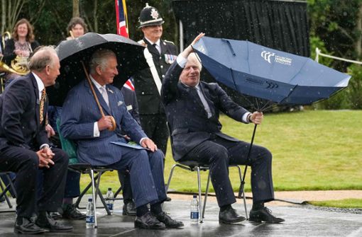 Der Regenschirm wollte nicht so, wie Boris Johnson wollte – und Prinz Charles (Mitte) war „amused“. Foto: AFP/CHRISTOPHER FURLONG