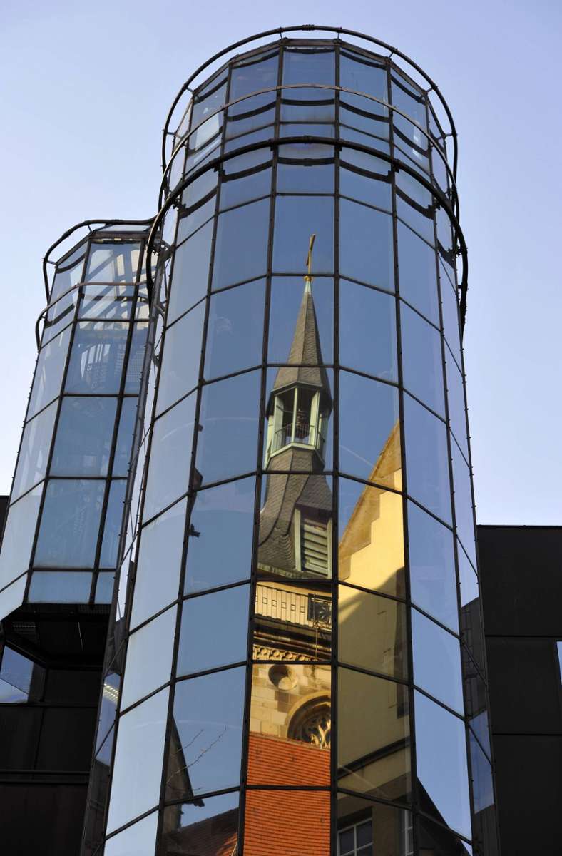 Das Bürogebäude der Commerzbank AG positioniert sich seit 1972 zwischen der gotischen Stiftskirche und dem ehemaligen Fruchtkasten in der Stuttgarter Stadtmitte. Den historischen Nachbargebäuden stellten Kammerer + Belz  eine Aluminium-Glas-Fassade gegenüber.
