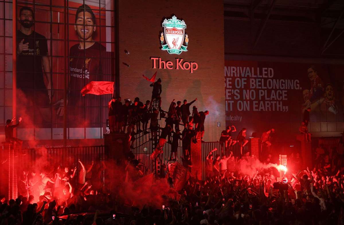 Fans feiern die englische Meisterschaft vor und auf dem Zaun des Anfield Stadions. Foto: AFP/OLI SCARFF