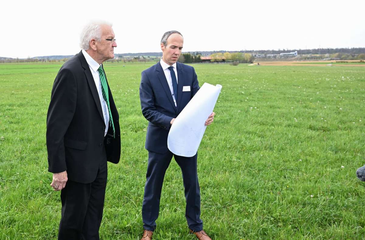 Winfried Kretschmann (links) auf der Wiese. Hier soll die neue Brennstoffzellenfabrik entstehen, Weinheims Bürgermeister Johannes Züfle mit einem Plan in der Hand. Foto: dpa/Bernd Weißbrod