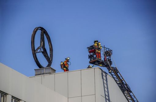 Feuerwehrleute stehen neben einem verbrannten Mercedes-Stern auf dem Dach eines Firmengebäudes. Foto: dpa/Dettenmeyer