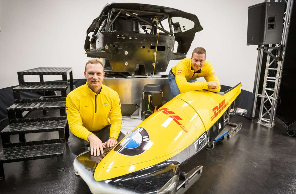 Die Bobfahrer Francesco Friedrich (li.) und Johannes Lochner vor dem Bob-Simulator im Hintergrund. Foto: BMW/Stefan Heigl