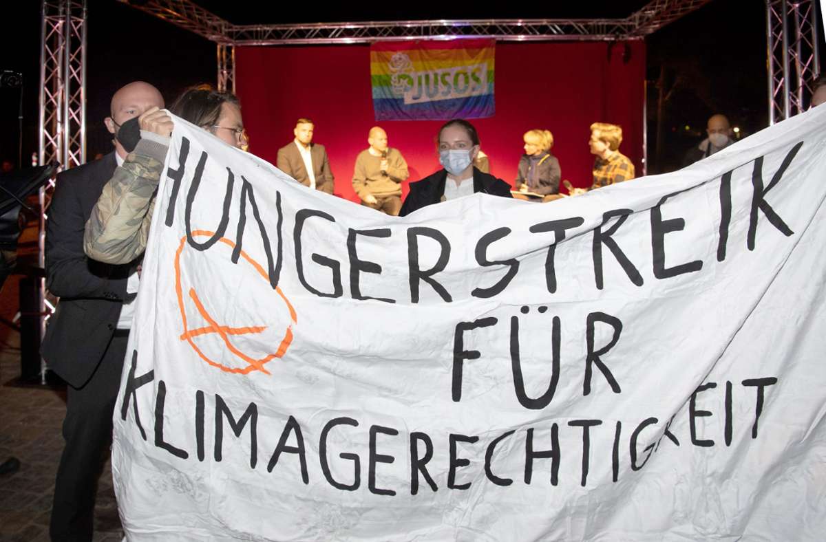 Klima-Aktivisten halten bei einer Wahlkampf-Veranstaltung mit SPD-Kanzlerkandidat Olaf Scholz ein Transparent in die Kamera. (Archivbild) Foto: dpa/Paul Zinken