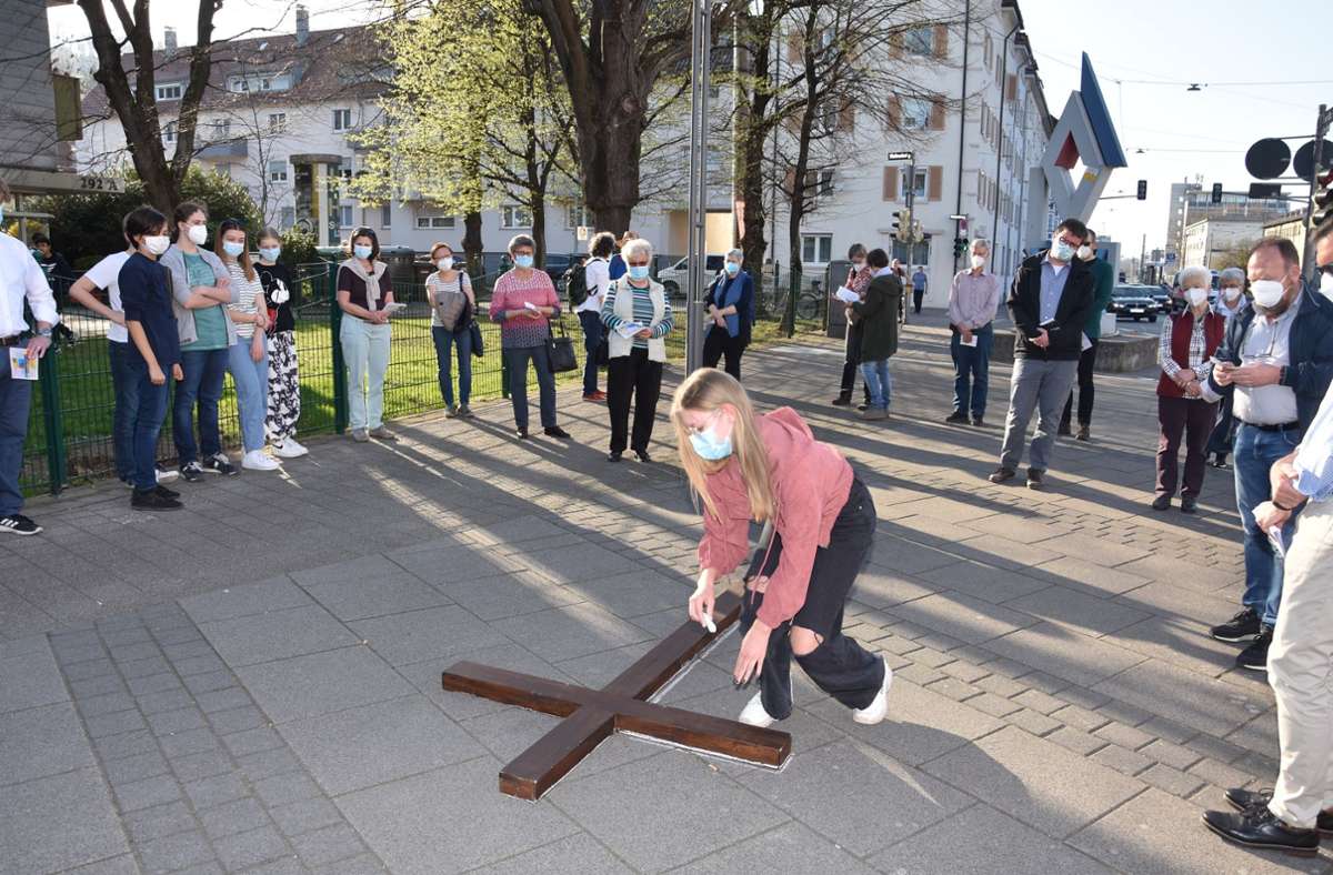 Eine Konfirmandin kennzeichnet die Umrisse des Holzkreuzes in der Ulmer Straße vor der Hajk-Skulptur.