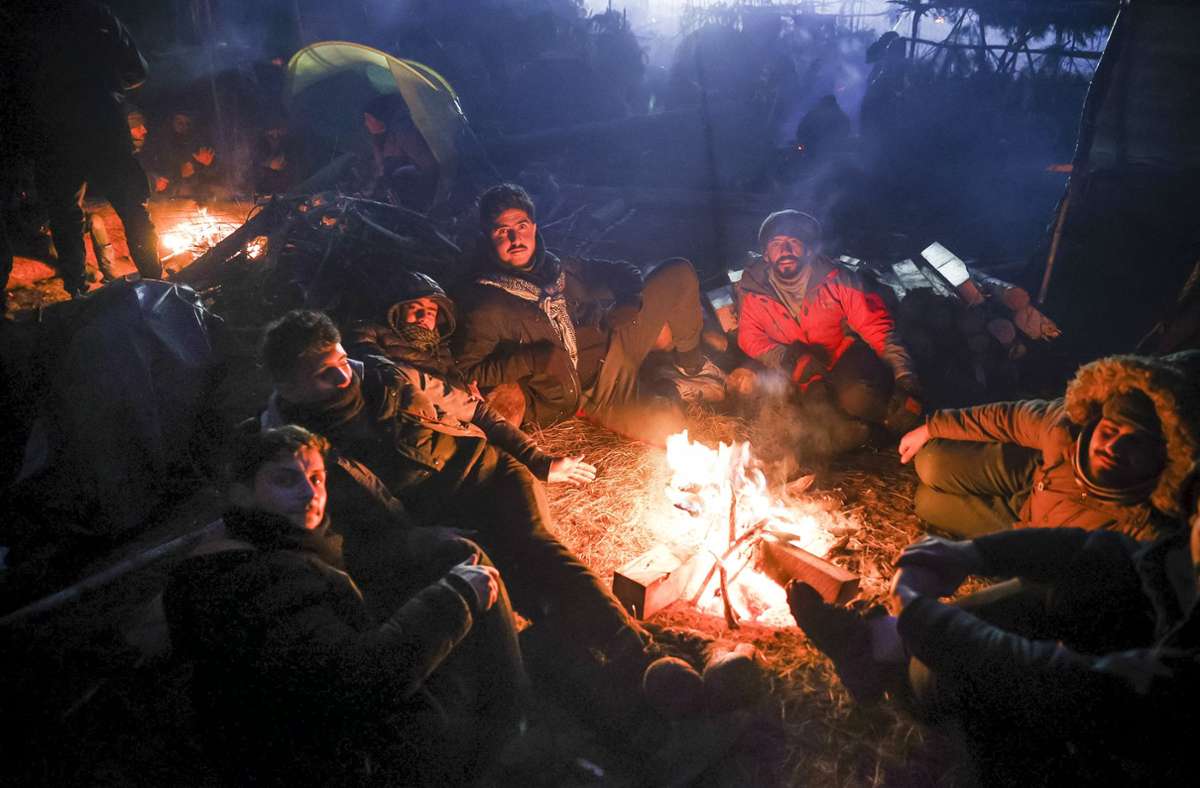 Migranten wärmen sich an einem Feuer an der weißrussisch-polnischen Grenze. Foto: dpa/Oksana Manchuk