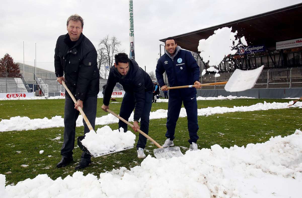 Der ehemalige Kickers-Trainer Guido Buchwald schippt zusammen mit Mahir Savranlioglu und Torwart Günäy Güvenc  Schnee auf Waldau.
