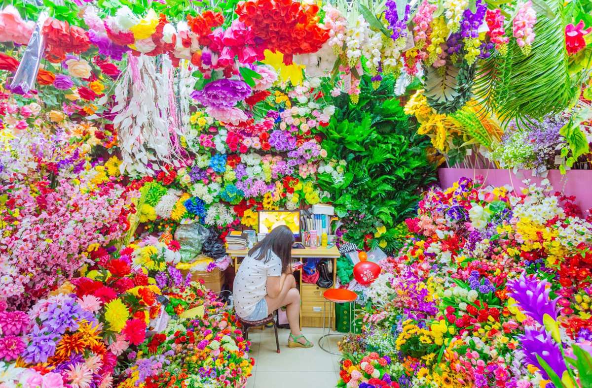 Eine Verkäuferin in einem Plastikblumenladen – Foto von Richard John Seymour, aus der Serie „Yiwu Commodity City, 2015 –  aus dem Ausstellungskatalog zur sehenswerten Schau „Plastik. Die Welt neu denken“ im Vitra Design Museum in Weil am Rhein.