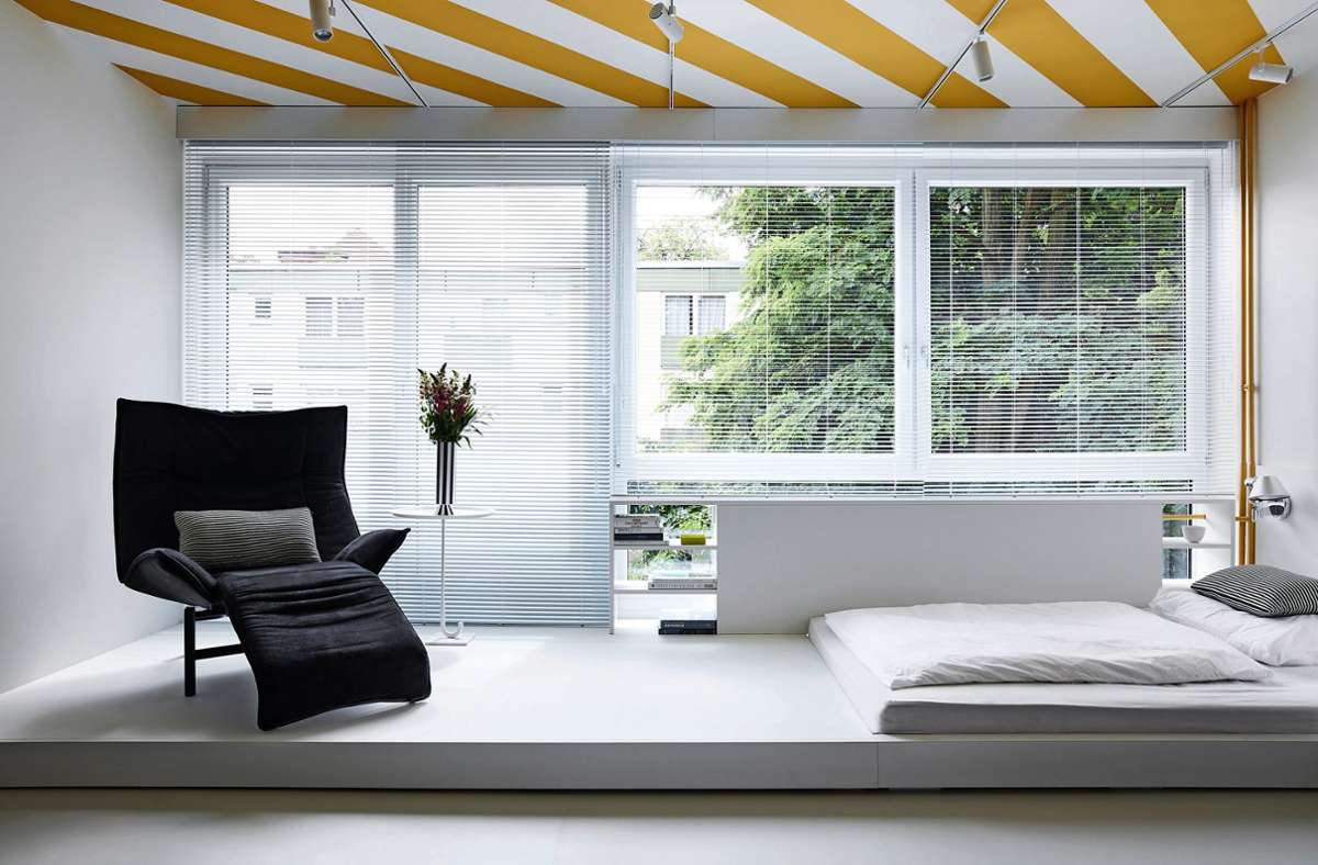 Kluge Idee – der gelb-weiß gestreifte Deckenanstrich  vermittelt eine sommerlich sonnige Atmosphäre. Der Schlafbereich im 30-Quadratmeter-Studio, gestaltet von Fabian Freytag, ist durch eine kleine Erhöhung vom Wohnbereich abgeteilt.