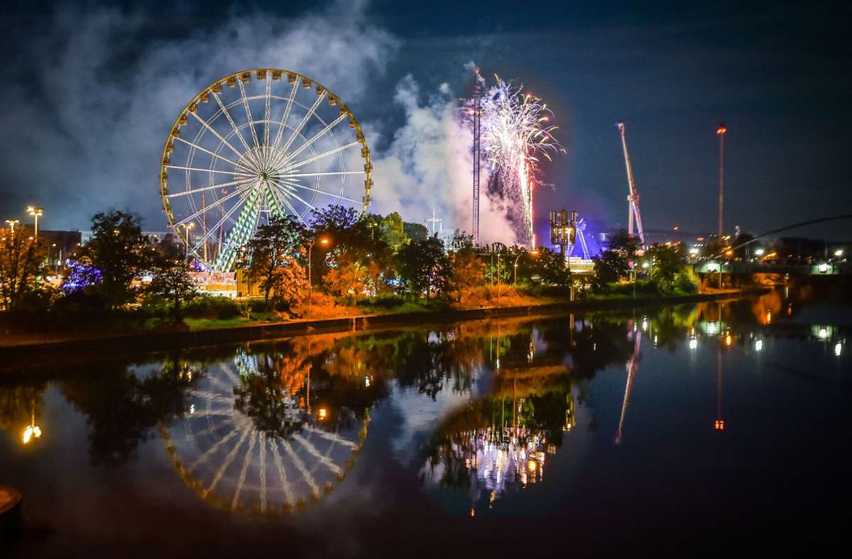 Stimmungsvoll: Das beleuchtete Riesenrad und das Wasen-Feuerwerk spiegeln sich im Neckar.