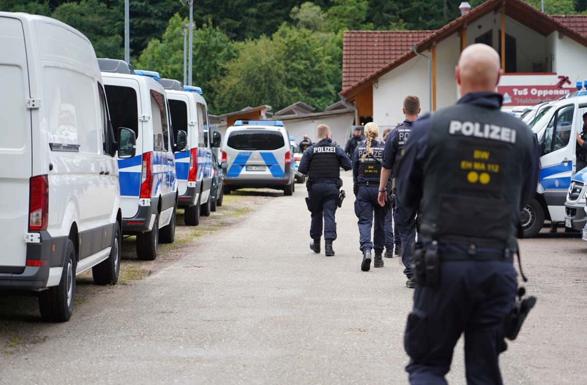 Oppenau: Polizisten gehen an einem Parkplatz an Polizeifahrzeugen vorbei. Foto: dpa/Benedikt Spether