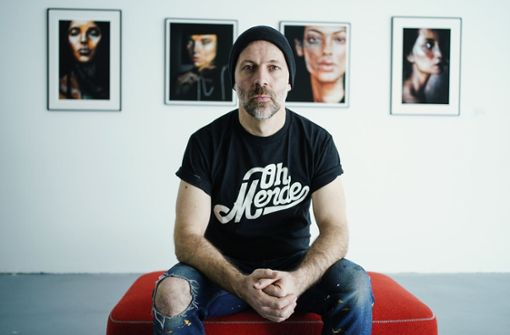 Der Street-Art-Künstler Falk Lehmann alias AKUT sitzt vor der Eröffnung der Ausstellung „Insights· vor einigen seiner Werke. Foto: dpa/Uwe Anspach