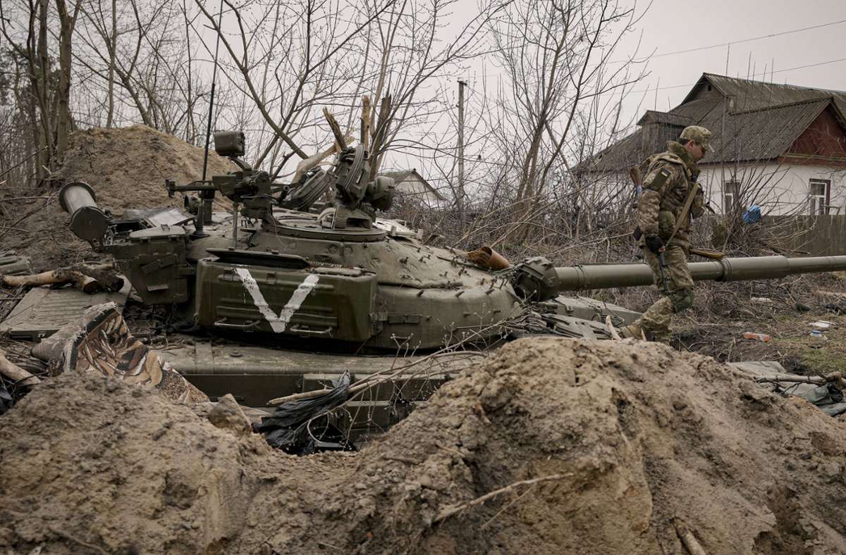 Ein ukrainischer Soldat geht an einem verlassenen Panzer der russischen Armee in der Stadt Andrijiwka  vorbei.
