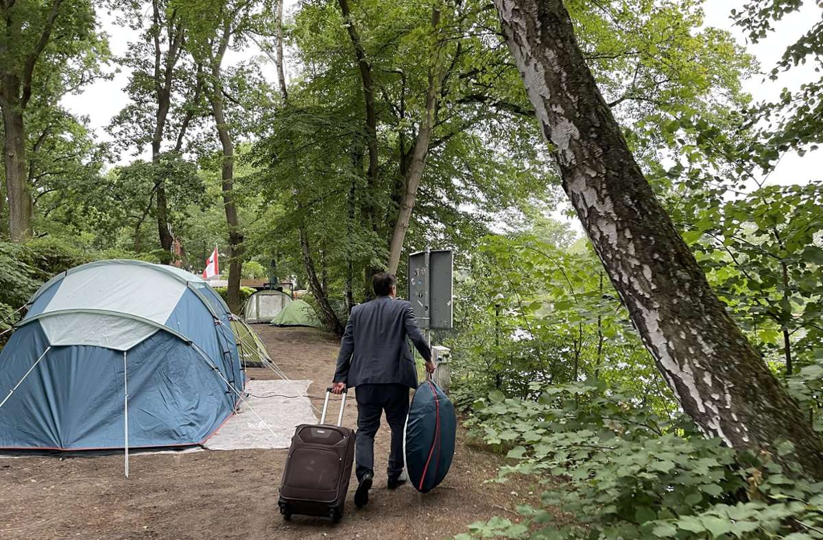 Mit Rollkoffer und eingepacktem Zelt geht es zum Eingang des Campingplatzes – vorbei an den noch schlafenden Mitcampern – dort wartet ein Taxi, das den Abgeordneten zum Büro fährt.