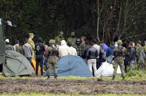 Migranten, die an der Grenze zu Belarus festsitzen, werden von polnischen Beamten umstellt. Foto: dpa/Czarek Sokolowski