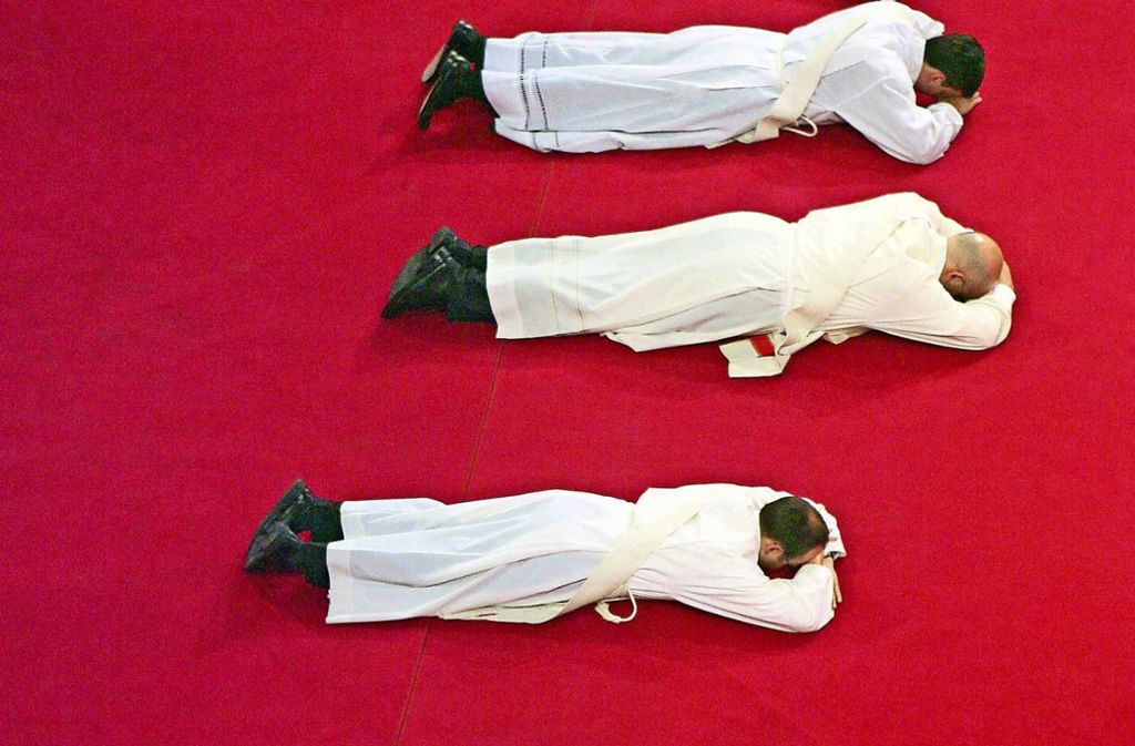 Priesteranwärter  liegen während ihrer Weihe zum Priester als Zeichen der Demut bäuchlings auf einem Teppich im Freiburger Münster. Foto: dpa/Rolf Haid