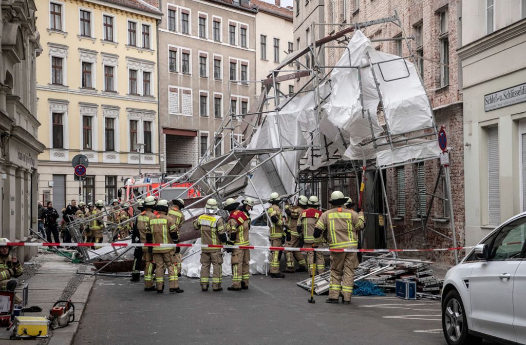 Feuerwehrleute stehen in der Berliner Sophienstraße an einem von Windböen eingestürzten Gerüst.