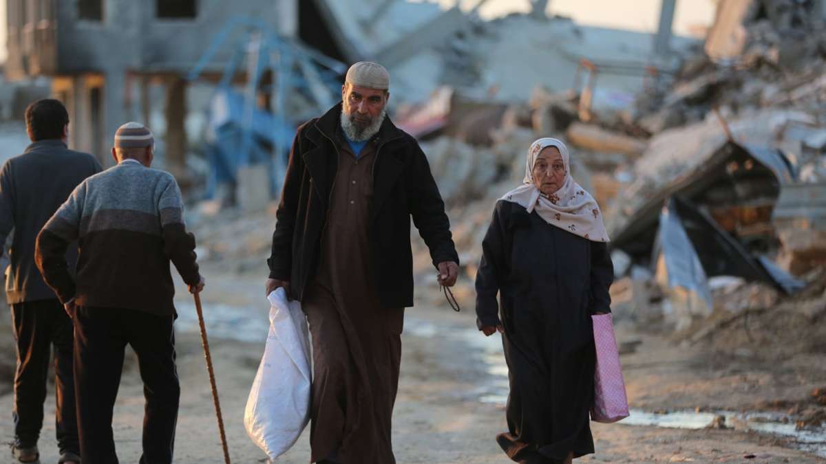 Menschen gehen an zerstörten Gebäuden im Flüchtlingslager Al-Maghazi im Zentrum des Gazastreifens vorbei. Das Bangen um eine Feuerpause vor Ramadan geht weiter.