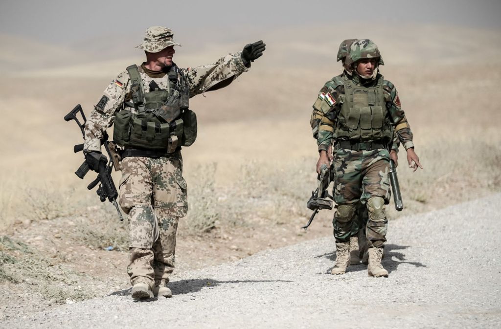 Ein Bundeswehrsoldat mit zwei irakischen Kollegen nahe Erbil. Derzeit ist unklar, ob der Einsatz ganz endet oder vielleicht sogar noch deutlich ausgeweitet wird. Foto: dpa/Michael Kappeler