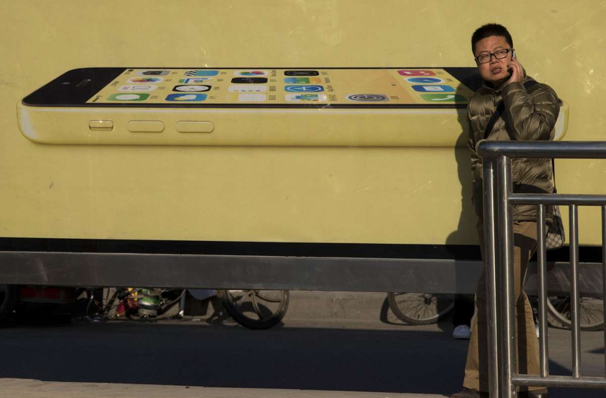 Passant in Peking vor einer iPhone-Reklame: Stimmt, telefonieren kann man mit den Dingern ja auch. Foto: AP