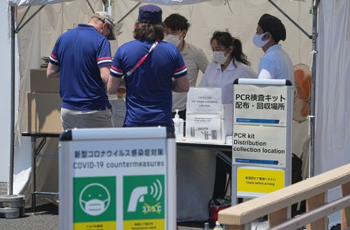 Zwei Männer geben ihre Speichelprobe für den Corona-PCR-Test in Tokio ab. Foto: dpa/Michael Kappeler