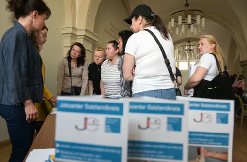 Aus der Ukraine geflüchtete Frauen holen sich Informationen am Stand eines Jobcenters. Foto: picture alliance/dpa/Heiko Rebsch