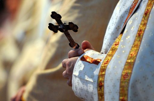 Ein katholischer Bischof hält während einer  Messe ein Kreuz in den Händen (Symbolbild). Foto: Peter Kneffel/dpa