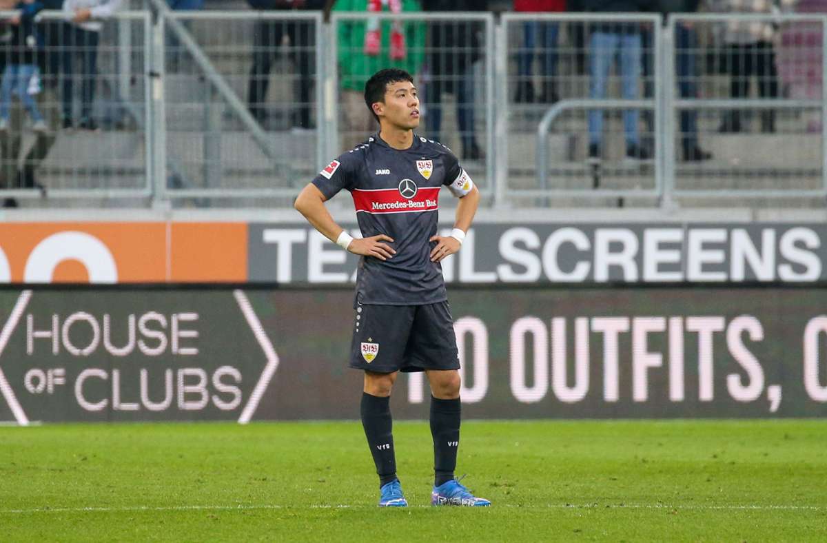 Ein ratloser und enttäuschter  Wataru Endo vom VfB Stuttgart steht nach einem der Augsburger Gegentore auf dem Platz.