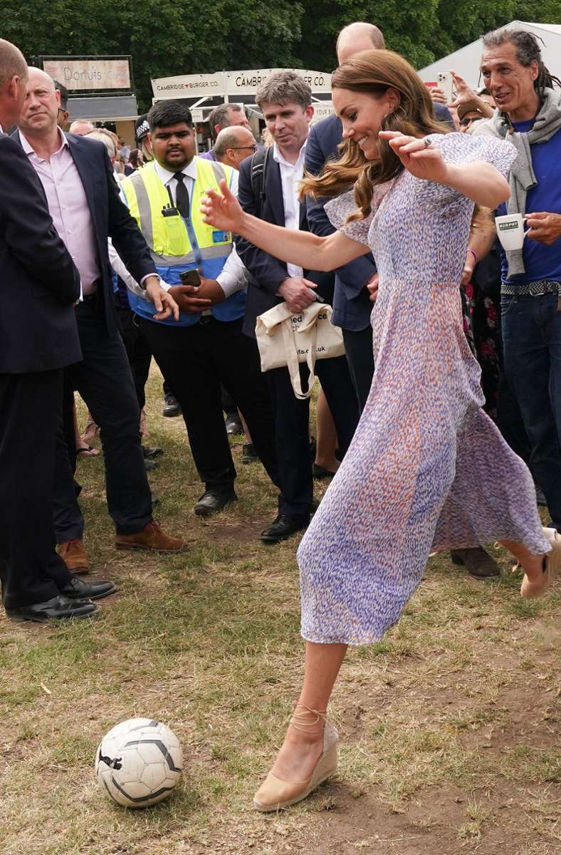 Kate, Herzogin von Cambridge, schießt einen Fußball auf der Pferderennbahn beim Besuch des Cambridgeshire County Day. Bei dieser Veranstaltung ließ sie den Mantel weg und wechselte die Schuhe.