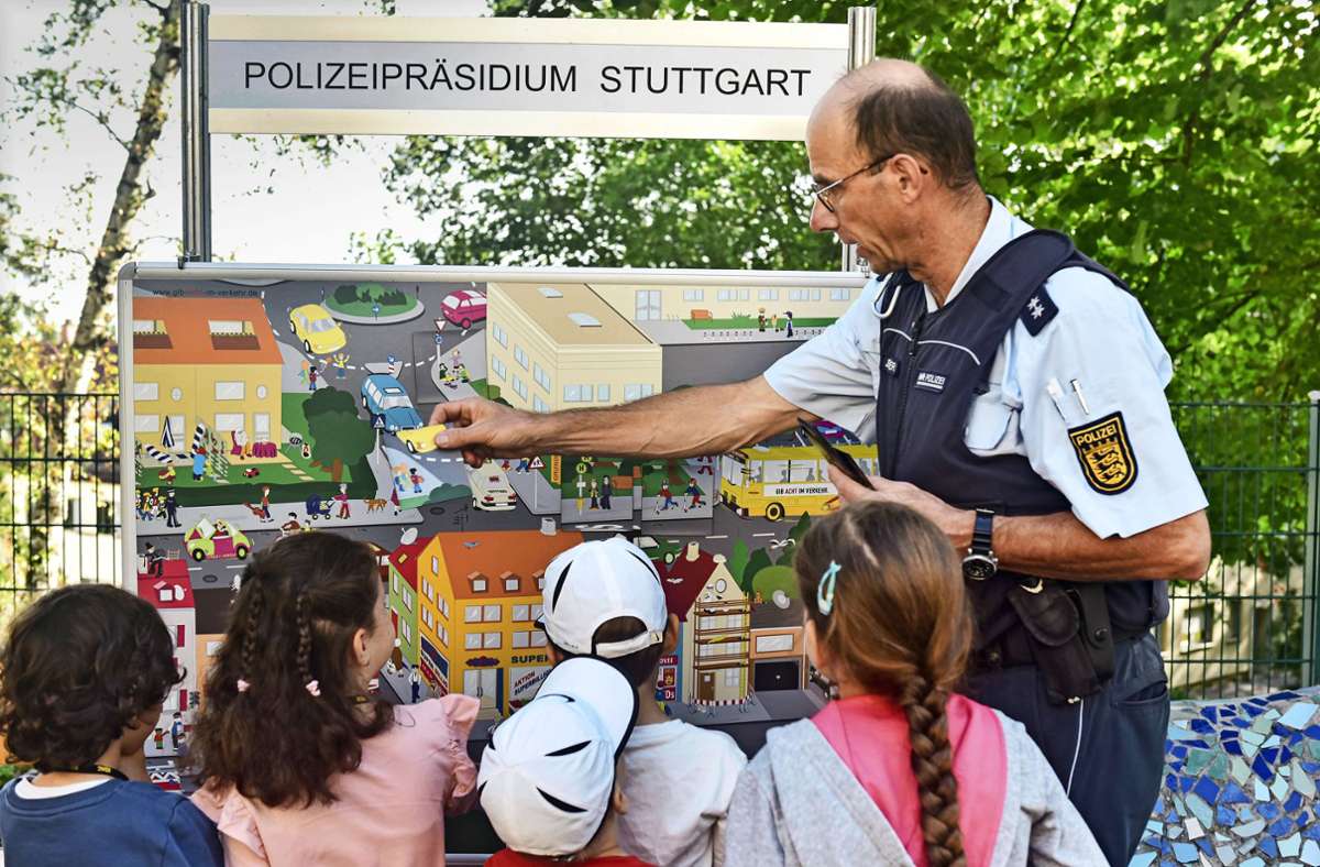 Ein Polizeibeamter erklärt Kindern anhand eines Wimmelbildes gefährliche Situationen auf dem Schulweg. Foto: Lichtgut/Max Kovalenko