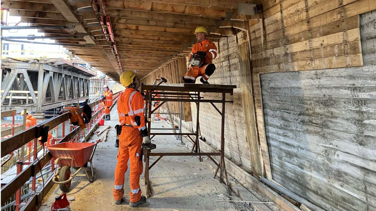 Bauarbeiter nehmen die Holzverschalung von der Betonwand ab.